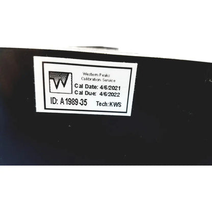 White rectangular calibration label with black text and logo on dark surface for welch allyn 9600 plus calibration tester