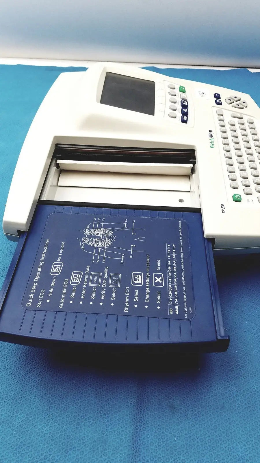 White welch allyn cp 200 ekg ecg monitor with blue tray displaying anatomical diagram and operating instructions