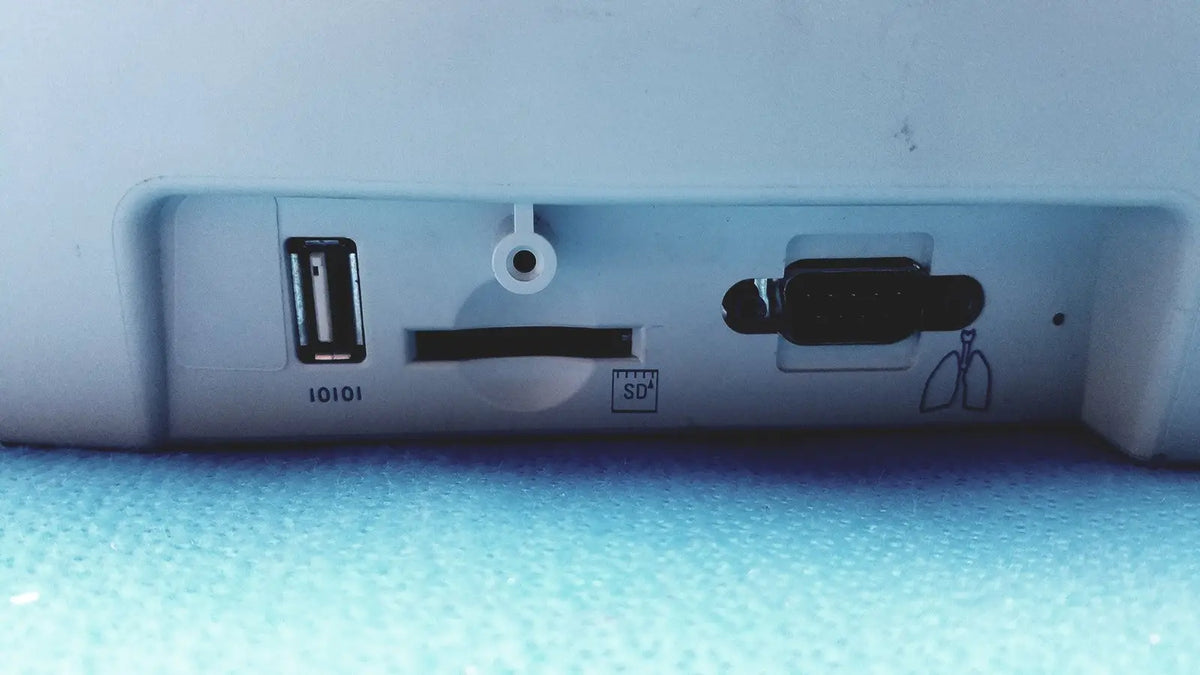 White plastic back side of welch allyn cp200 ekg monitor with usb port sd card slot and circular cable hole