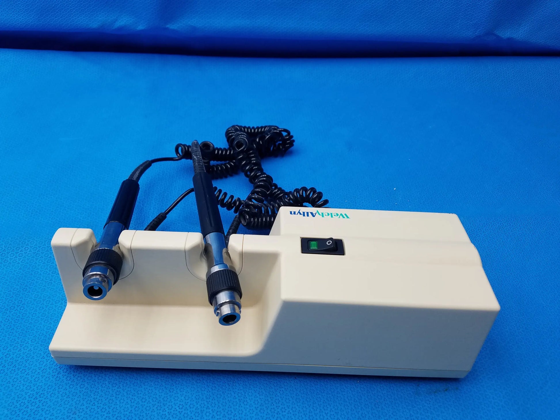 Cream-colored welch allyn diagnostic laser device with black-handled probes and coiled cables branded weldaly