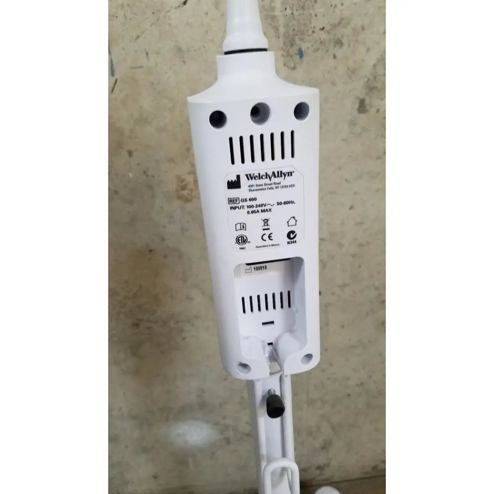 White plastic welch allyn gs 600 exam light with ventilation slots and black power cord on rolling stand rear view
