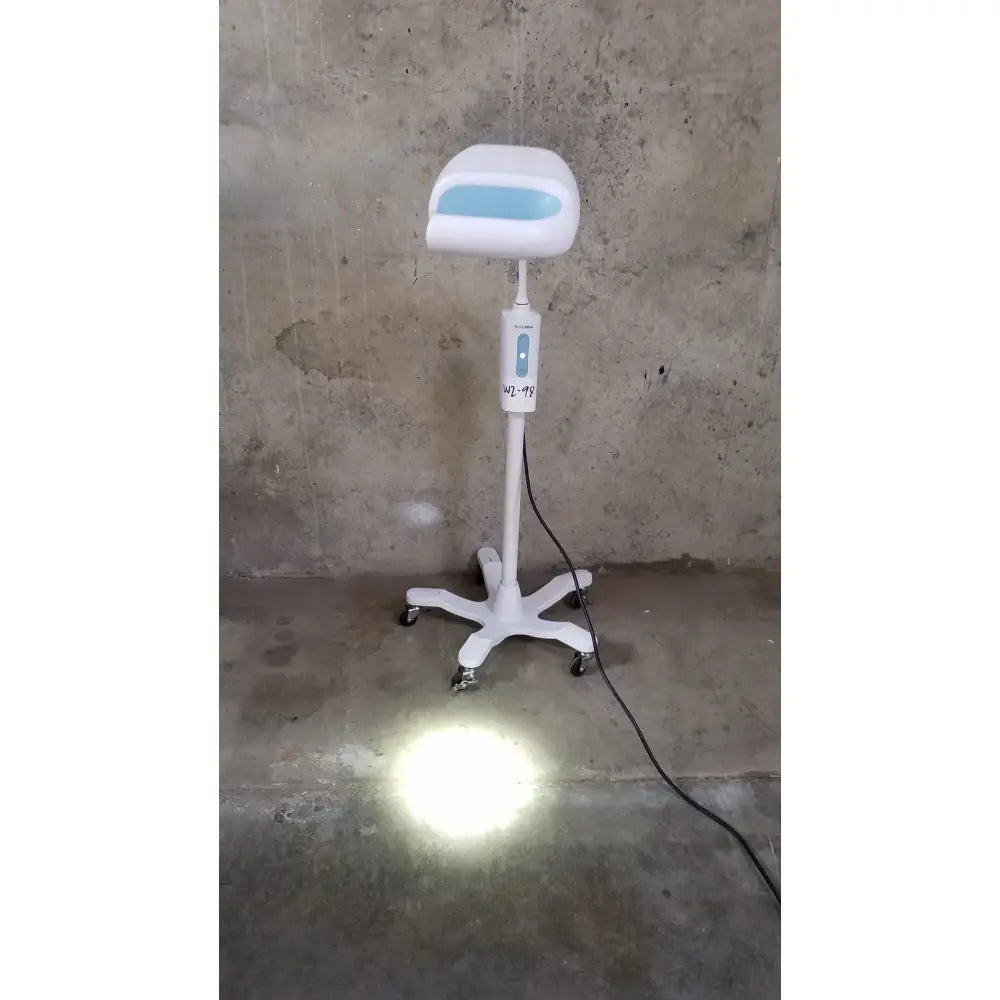 White adjustable salon chair with light blue illuminated seat panel and control unit next to welch allyn exam light rolling stand