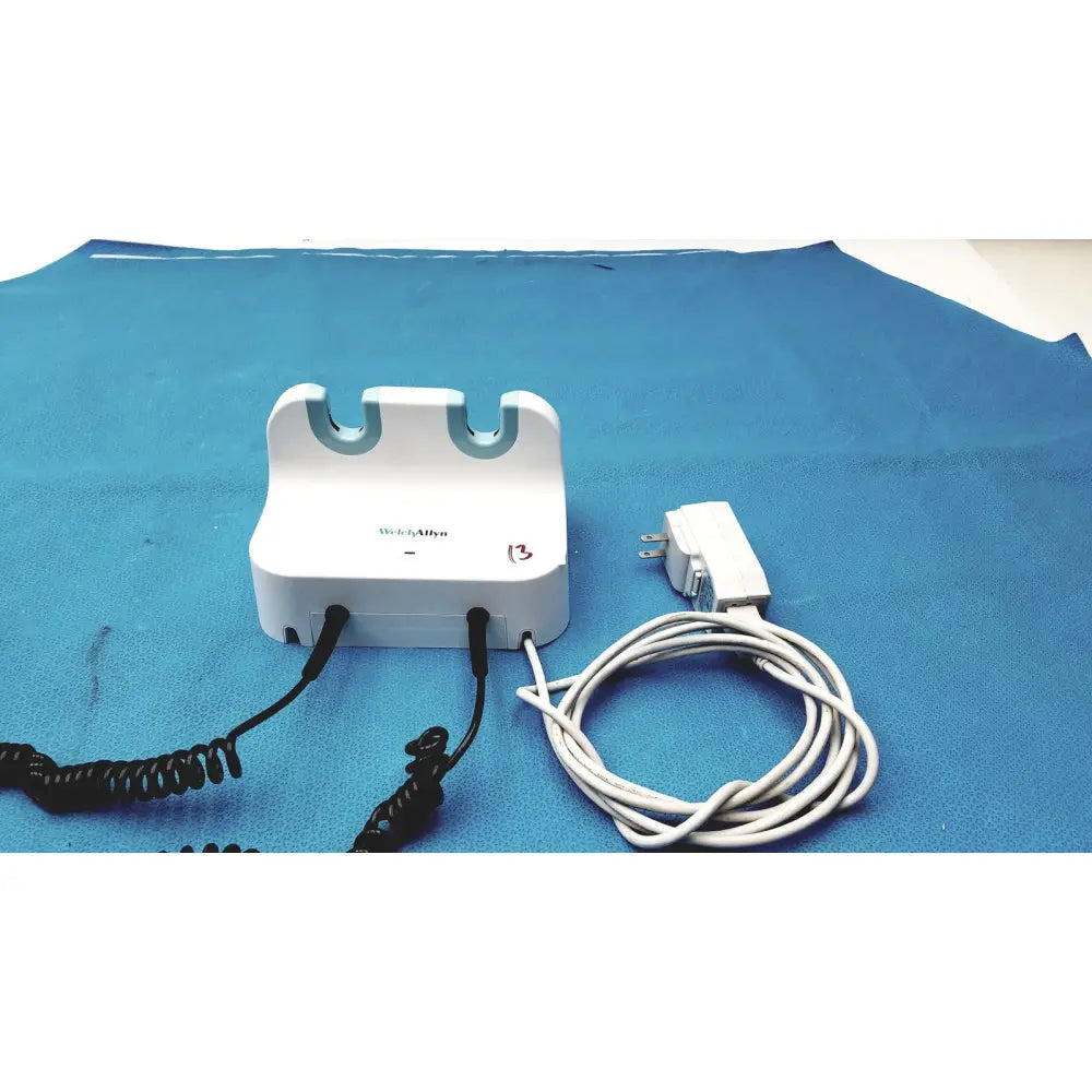 White plastic welch allyn gs 777 wall transformer with blue curved slots and black coiled cords for ophthalmoscope otoscope