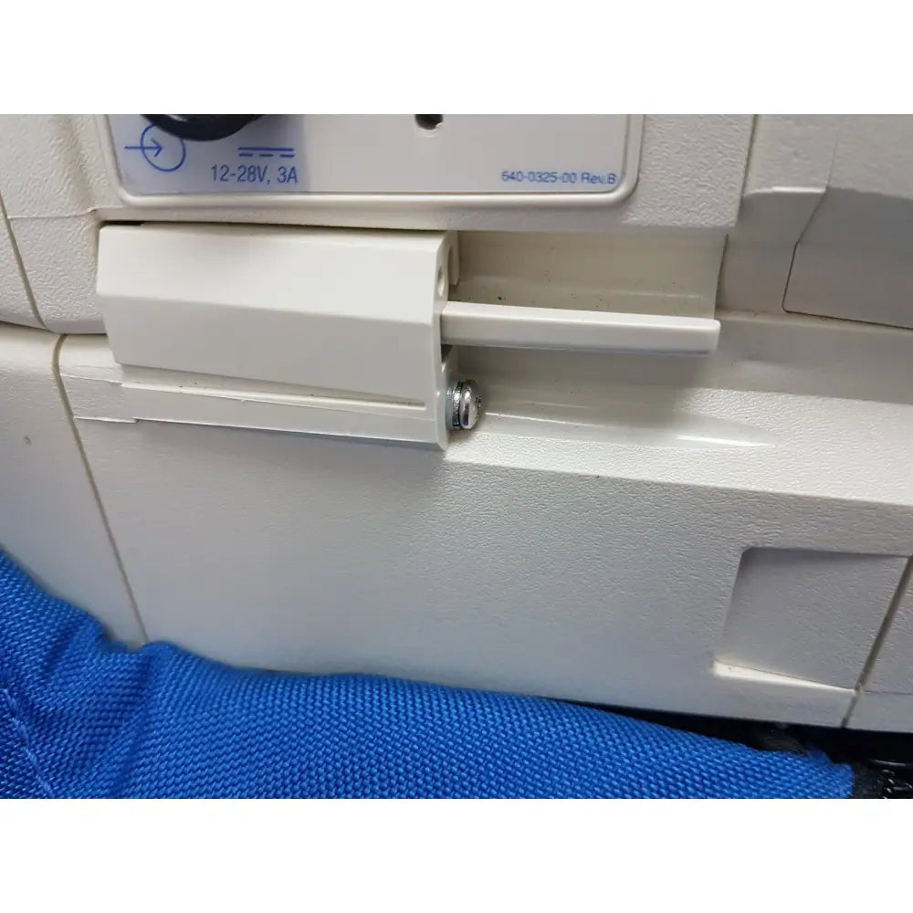White plastic power switch with silver screw and voltage label on the back of welch allyn propaq encore patient monitor
