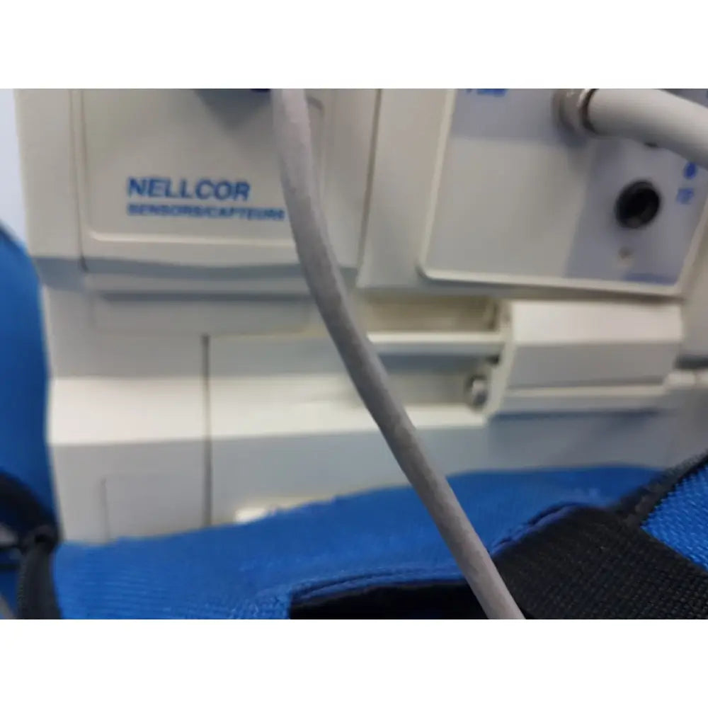 Gray textured cable connected to white medical equipment labeled nell cor on welch allyn propaq encore patient monitor