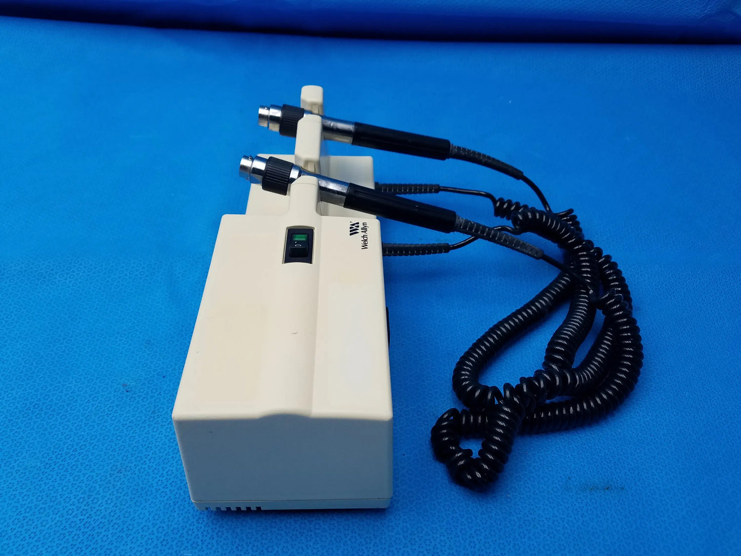 Cream-colored welch allyn diagnostic series transformer with two black-handled probes and green power indicator light