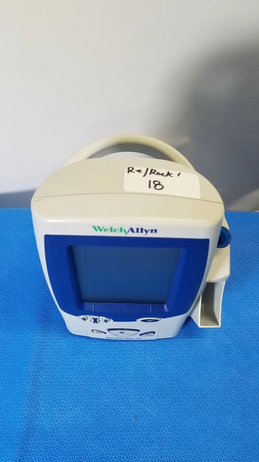 White and blue welch allyn spot vital signs LXi patient monitor with handle, screen, and control buttons
