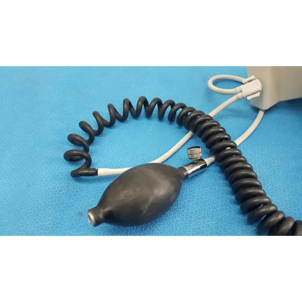 Black rubber bulb with coiled tubing and white connector attached to welch allyn tycos mount aneroid blood pressure monitor