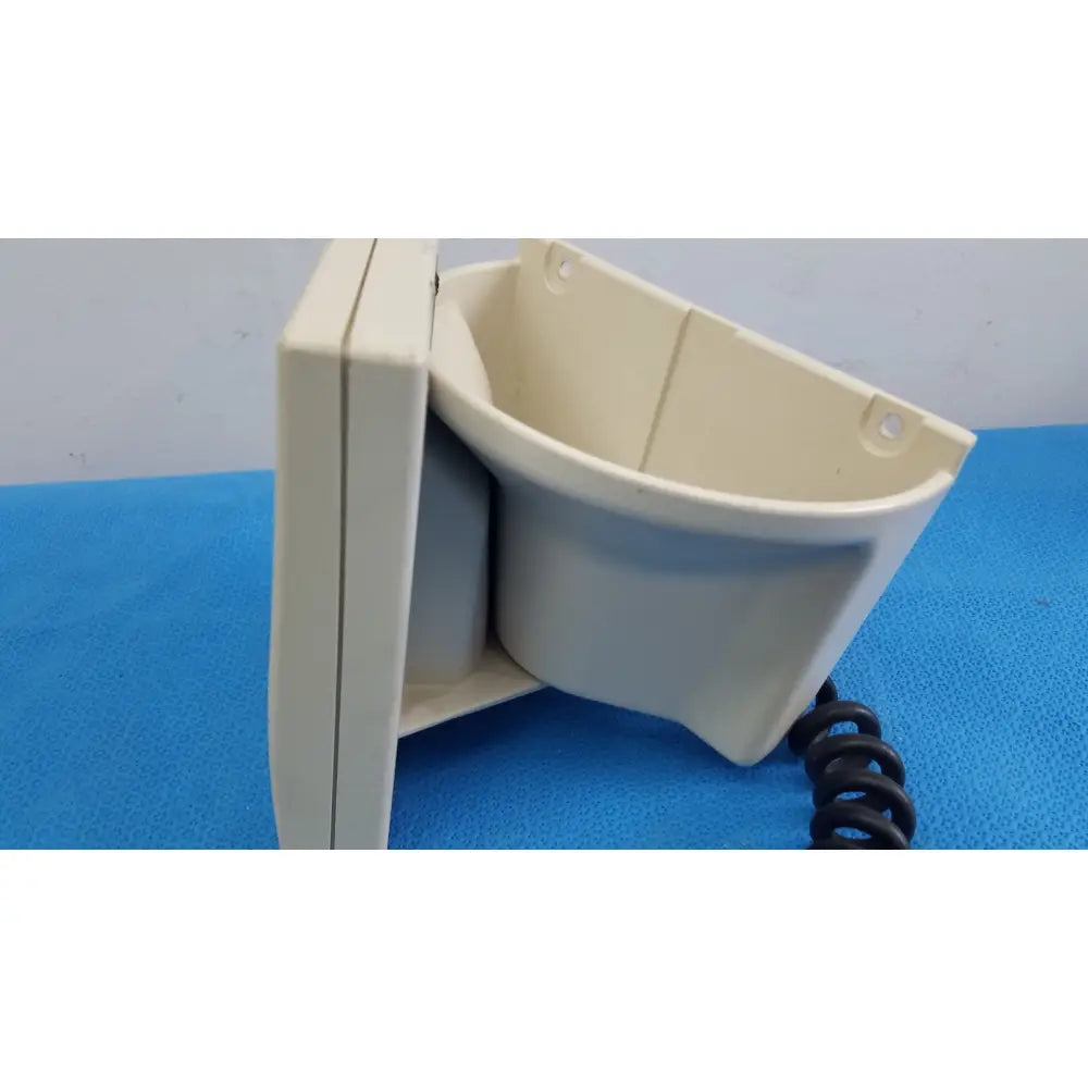 Beige plastic wall-mounted phone receiver with coiled black cord in welch allyn tycos mount aneroid sphygmomanometer monitor