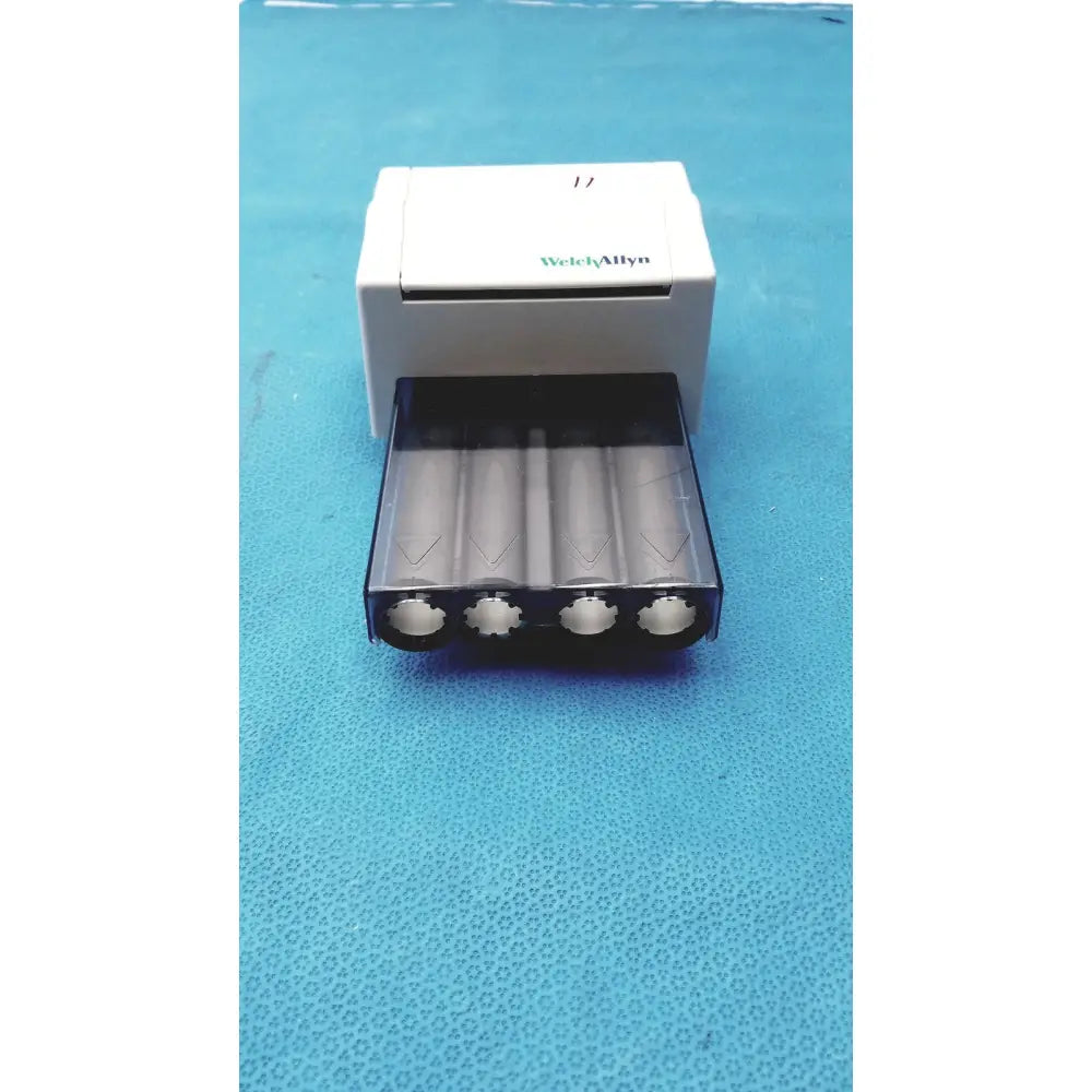 White welch allyn universal battery charger with black tray holding four cylindrical batteries for universal kleenspec single use dispenser