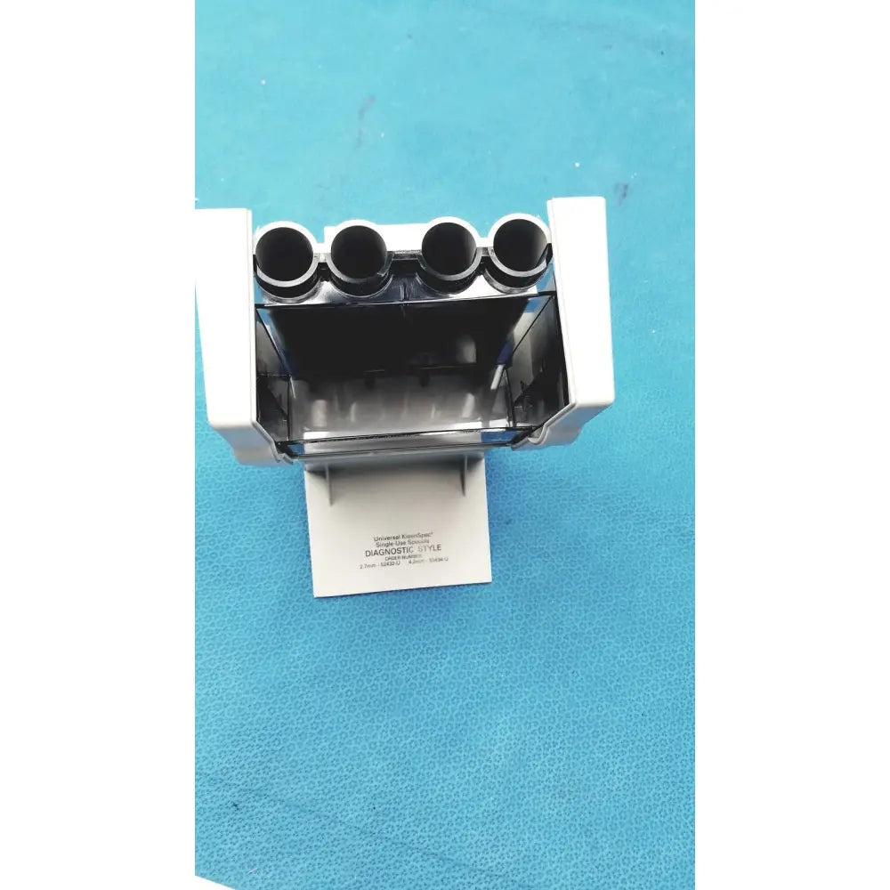 White plastic universal kleenspec single use specula dispenser with four circular slots and transparent front panel