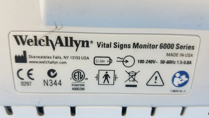 White welch allyn vital signs monitor 6000 series with cables blood pressure cuffs and technical specifications label visible