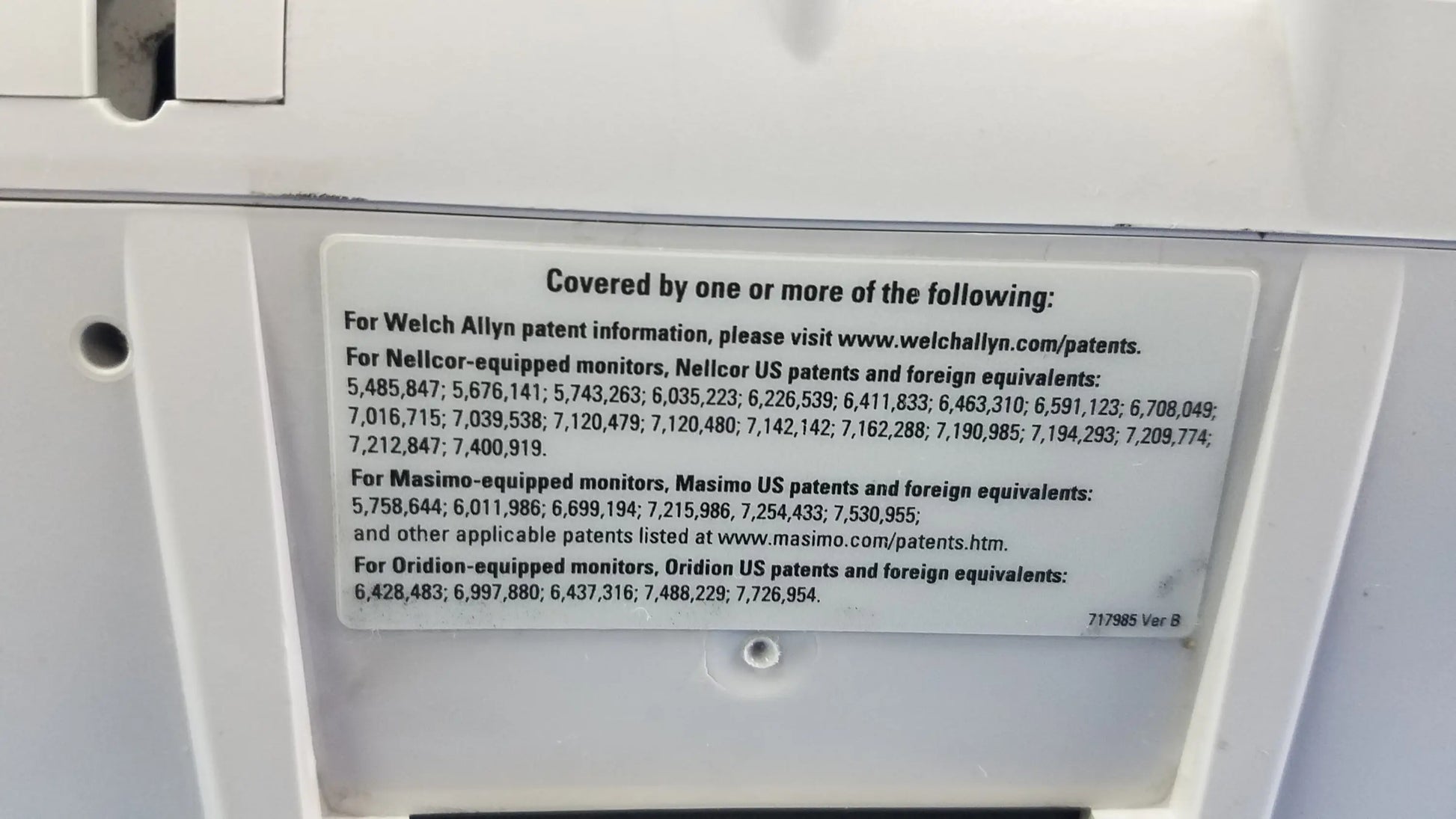 White rectangular patent information label with black text on the back of welch allyn vital signs monitor 6000 series with blood pressure cuffs