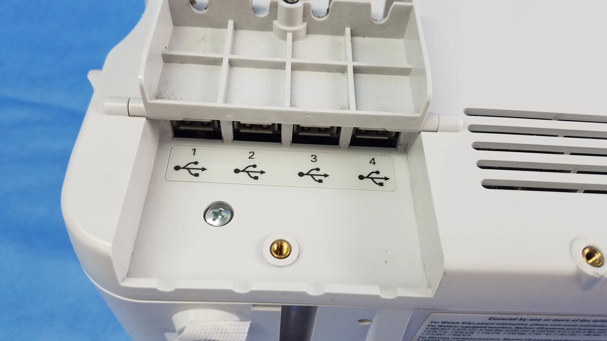 Back side of white plastic vital signs monitor 6000 series with four usb ports and blood pressure cuffs connection points