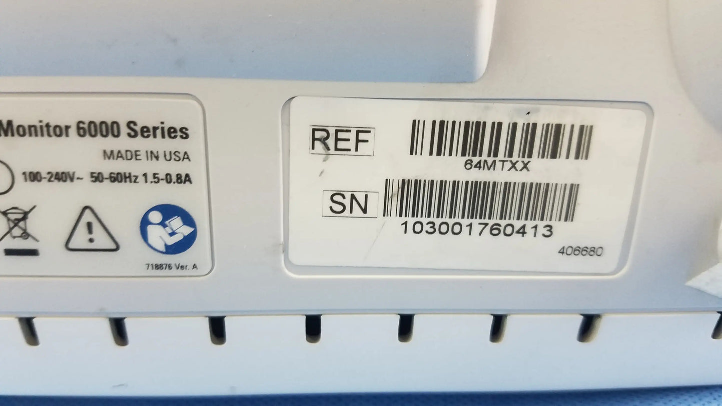 White plastic label with black text and barcode on the back of a Welch Allyn vital signs monitor 6000 series with blood pressure cuffs