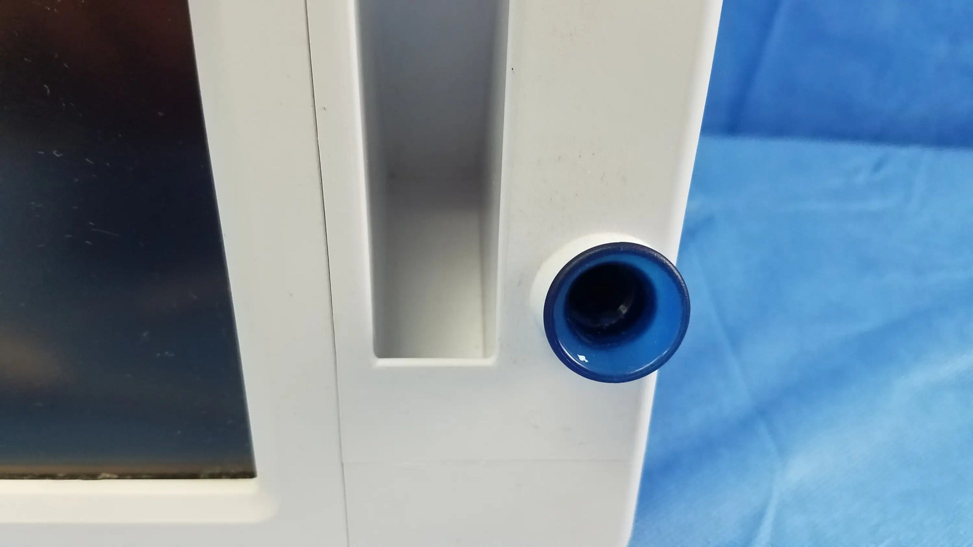 White plastic cabinet with a blue circular knob on the side of welch allyn vital signs monitor with blood pressure cuffs