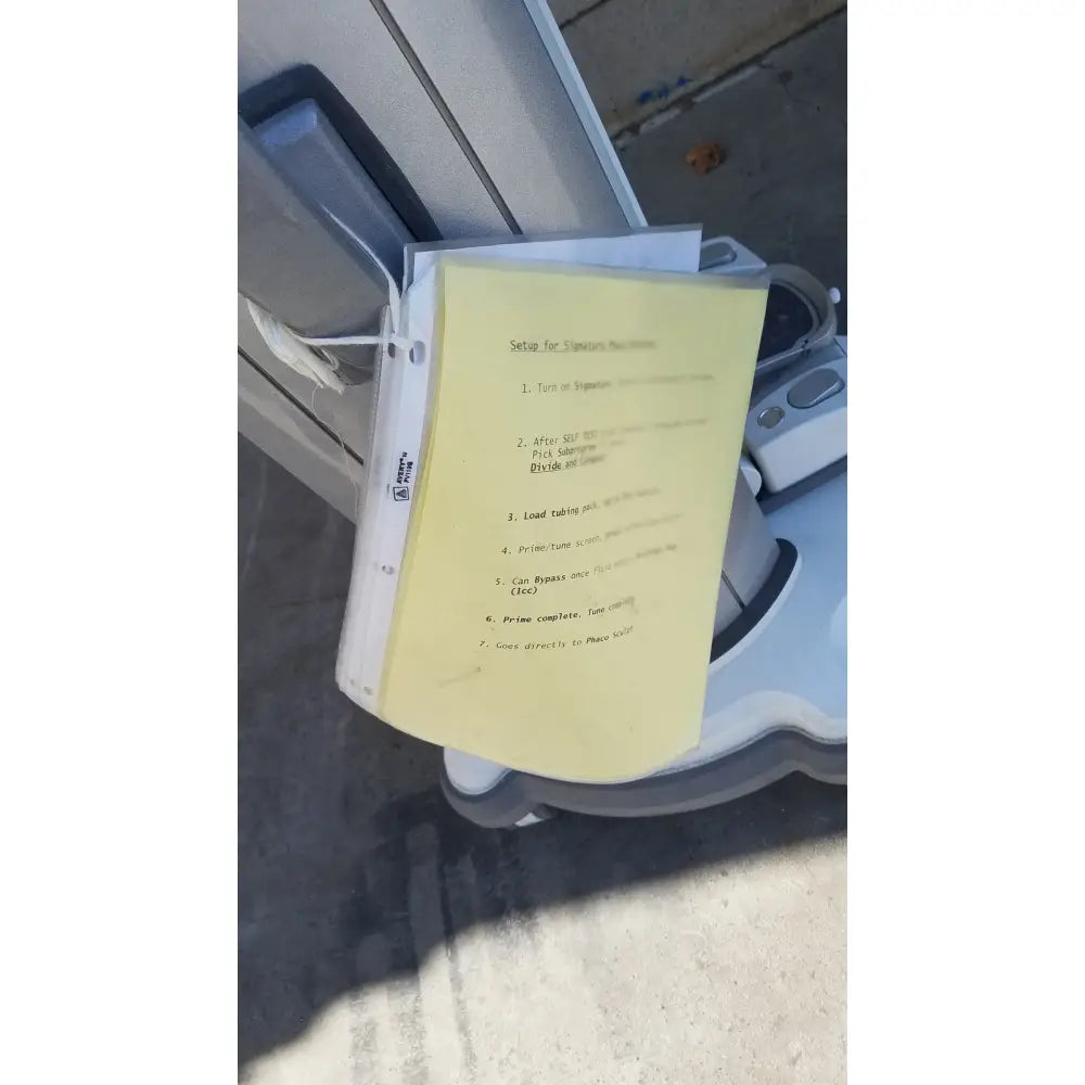Yellow paper with machine instructions resting on the edge of a gray whitestar signature phacoemulsifier robotic vacuum cleaner