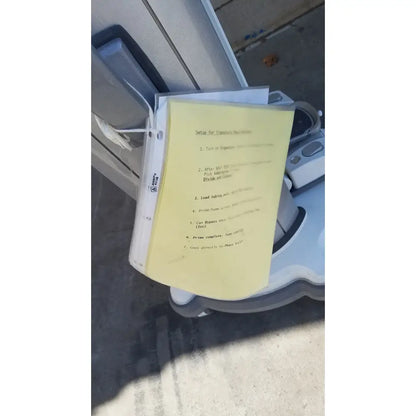 Yellow paper with machine instructions resting on the edge of a gray whitestar signature phacoemulsifier robotic vacuum cleaner