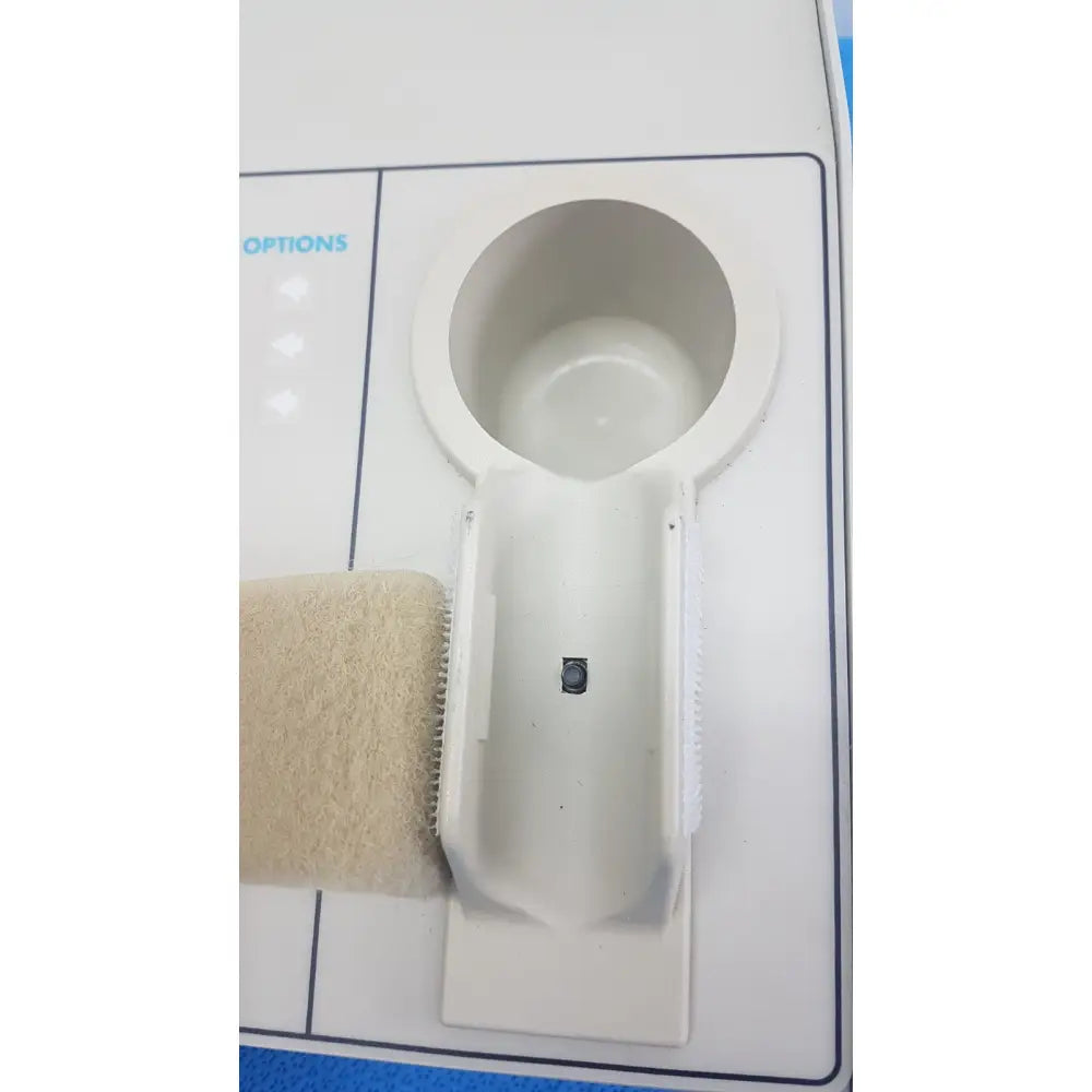 White plastic cup holder with beige textured strap attached to williams 6100 ultrasound therapeutic device side
