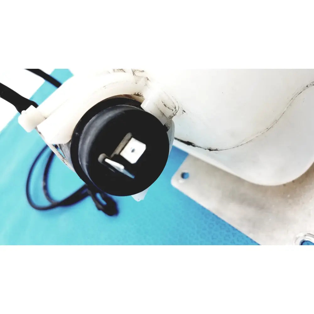 Black plastic cap with white connector and metal prongs attached to translucent white washer fluid reservoir tank