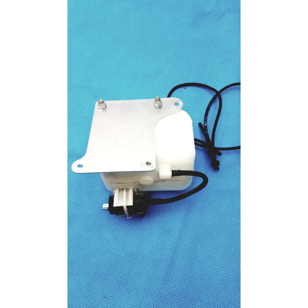 White plastic windshield washer fluid reservoir tank with cap metal mounting plate and black electrical wiring visible