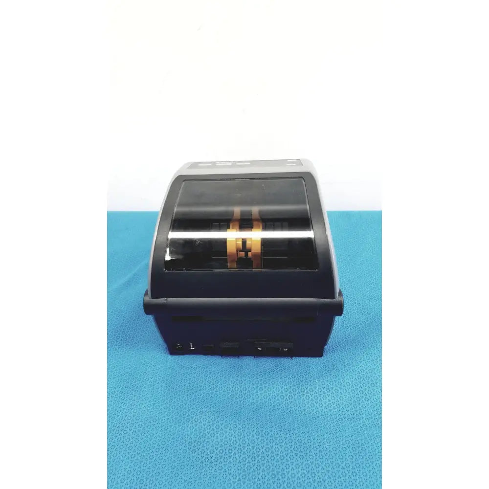 Black and silver zebra zd620 thermal transfer desktop label printer with transparent front panel showing gold internal components