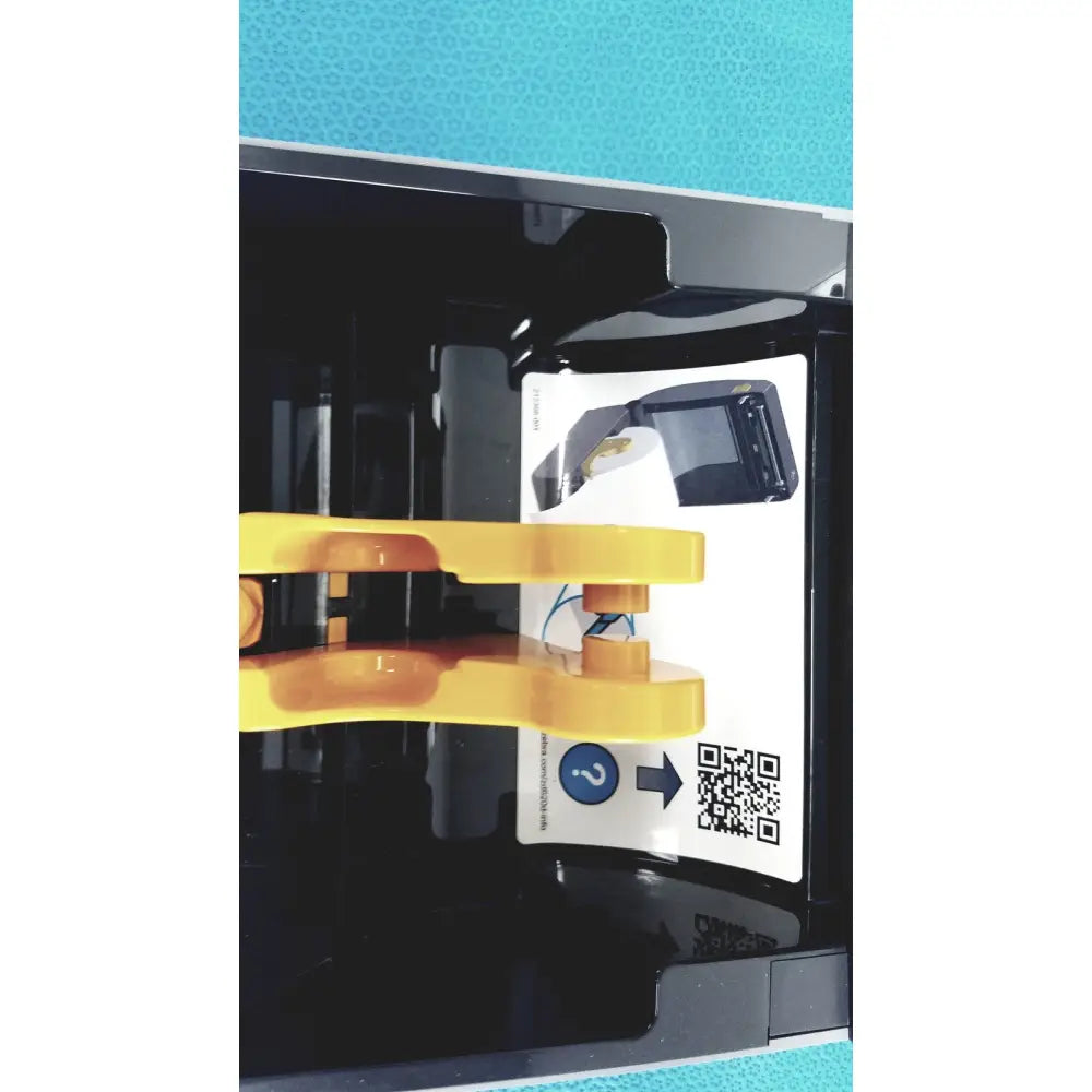 Yellow plastic clamp holding a black device with qr code label on the back of a zebra zd620 thermal transfer desktop printer