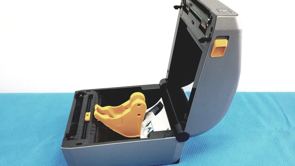 Gray zebra zd620 thermal transfer desktop label printer with yellow plastic component inside its open casing