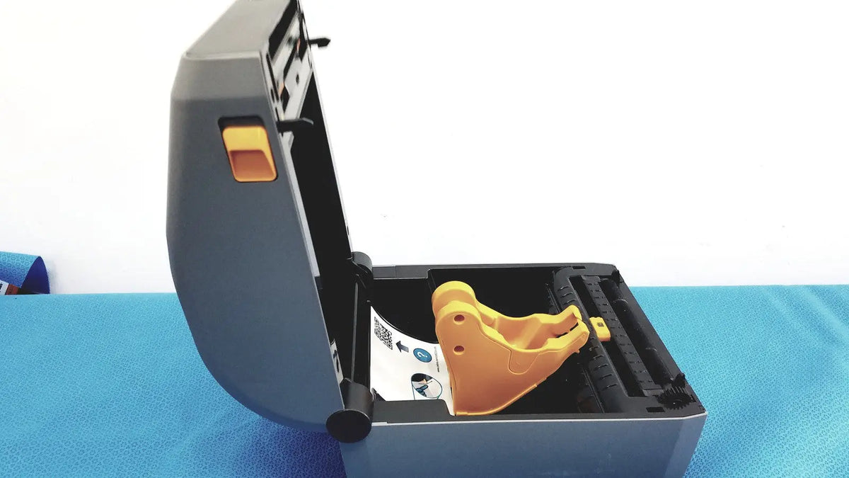 Gray and orange zebra zd620 thermal transfer desktop label printer showing yellow plastic component inside housing