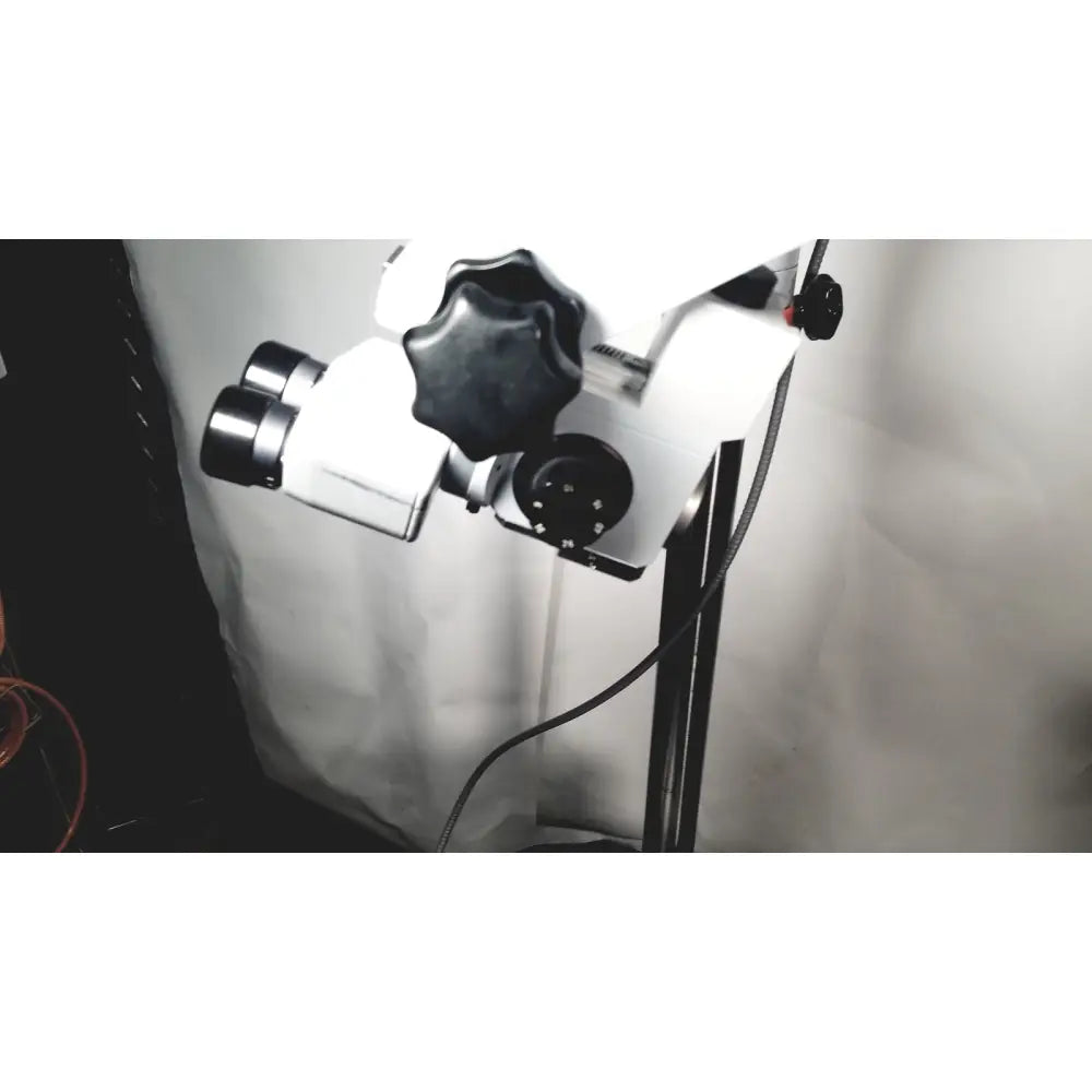White and black dual-lens zeiss opmi-1 prescotts mark ii stereo microscope mounted on a floor stand with adjustable knobs