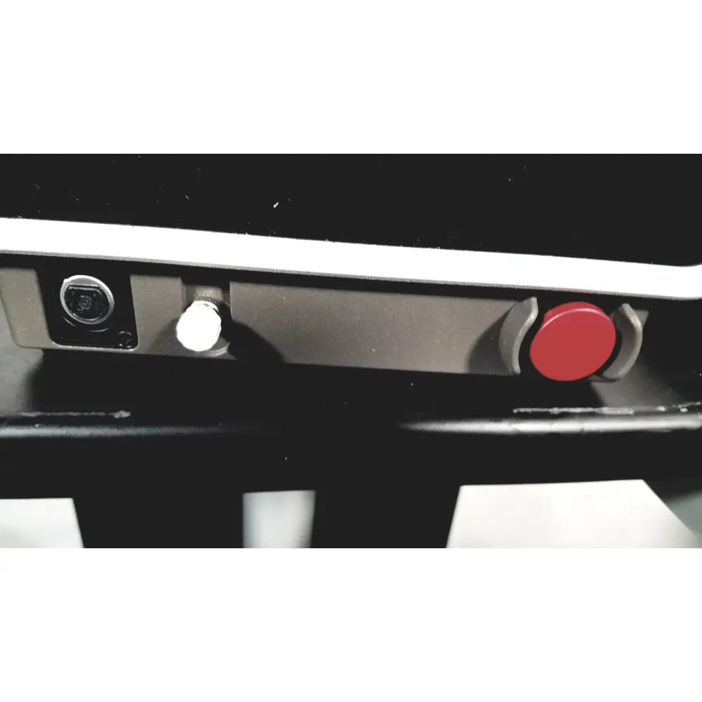 Red circular emergency stop button with gray housing on the zepto precision pulse capsulotomy power console stand