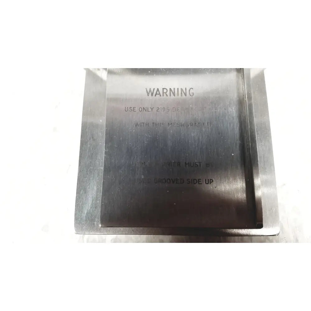 Silver metallic rectangular mesh plate with engraved warning text on the back side of zimmer meshgraft dermatome ii 2195-100