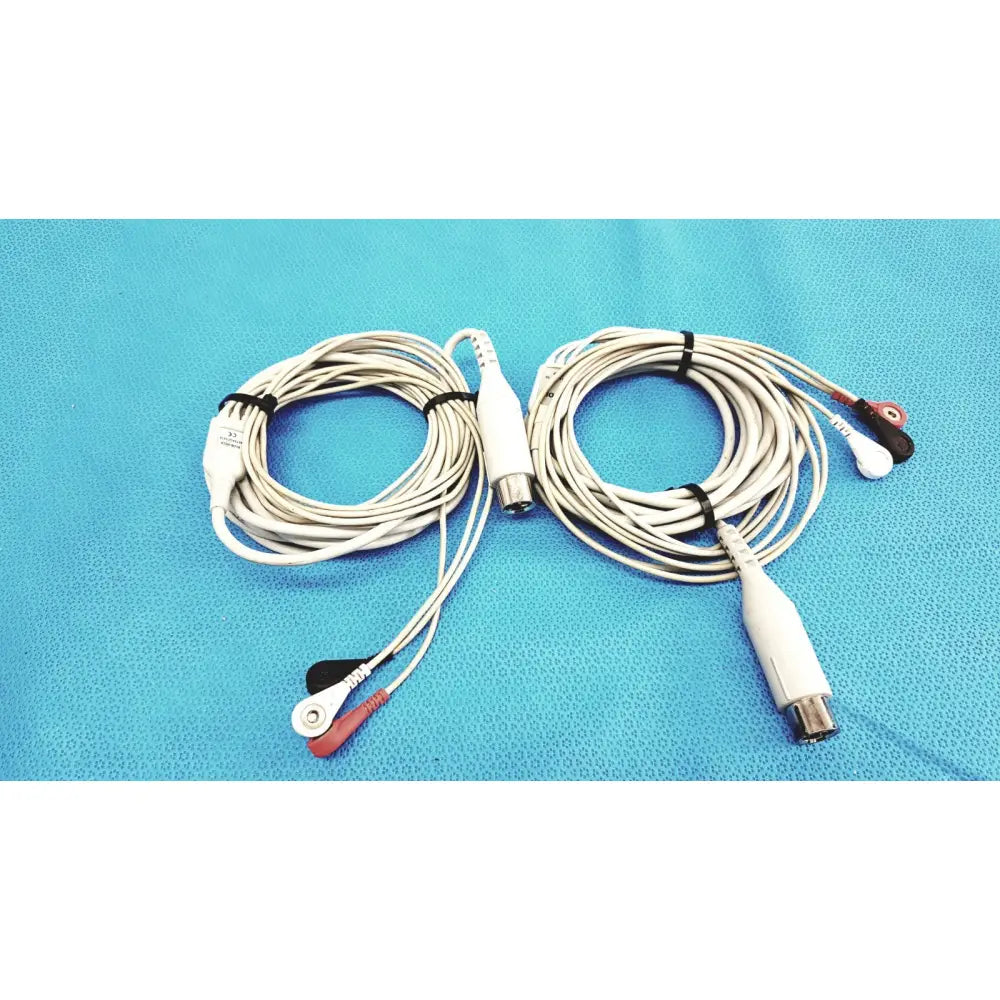 White Zoll 3-lead ECG EKG patient monitoring cables with red and black electrode tips coiled on a blue surface