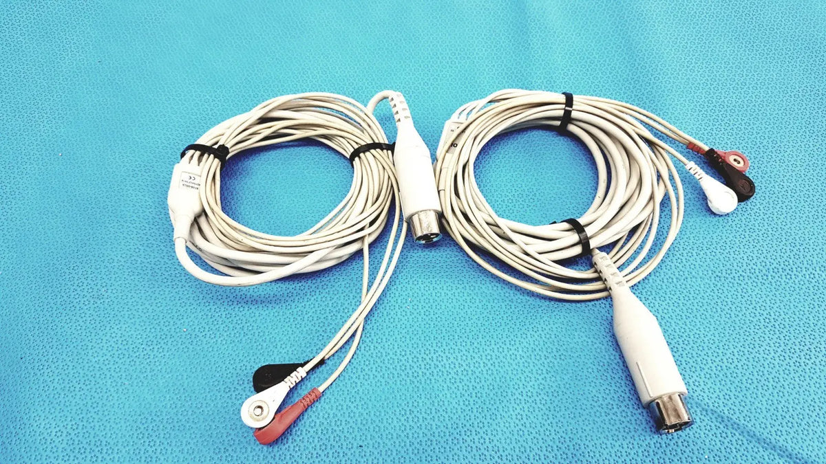 White Zoll 3-lead ECG EKG patient monitoring cables with red and black electrode tips coiled on a blue surface