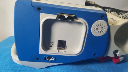 Blue and white zoll r series als patient monitor with hinged compartment revealing internal port and surepower battery pack