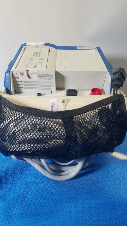 Blue and white zoll r series als patient monitor with black mesh pouch and surepower battery pack attached front