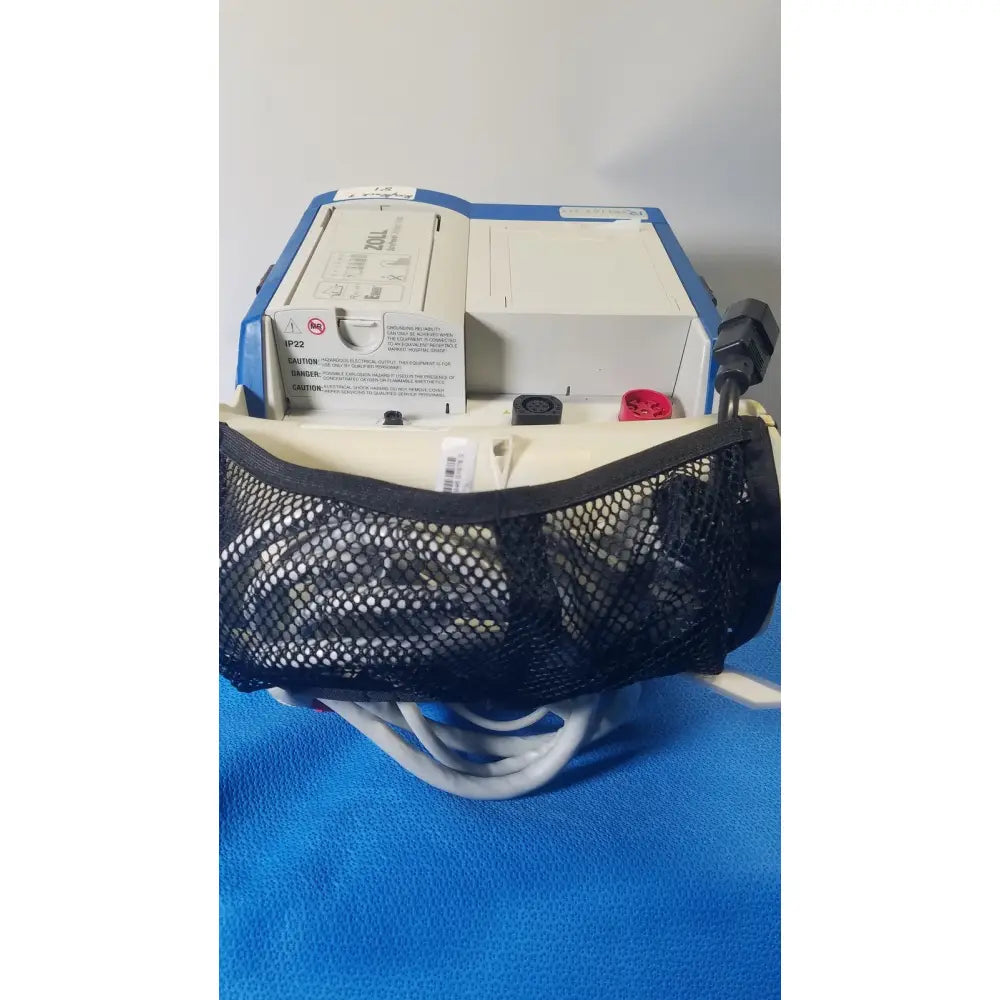 Blue and white zoll r series als patient monitor with black mesh pouch and surepower battery pack attached front