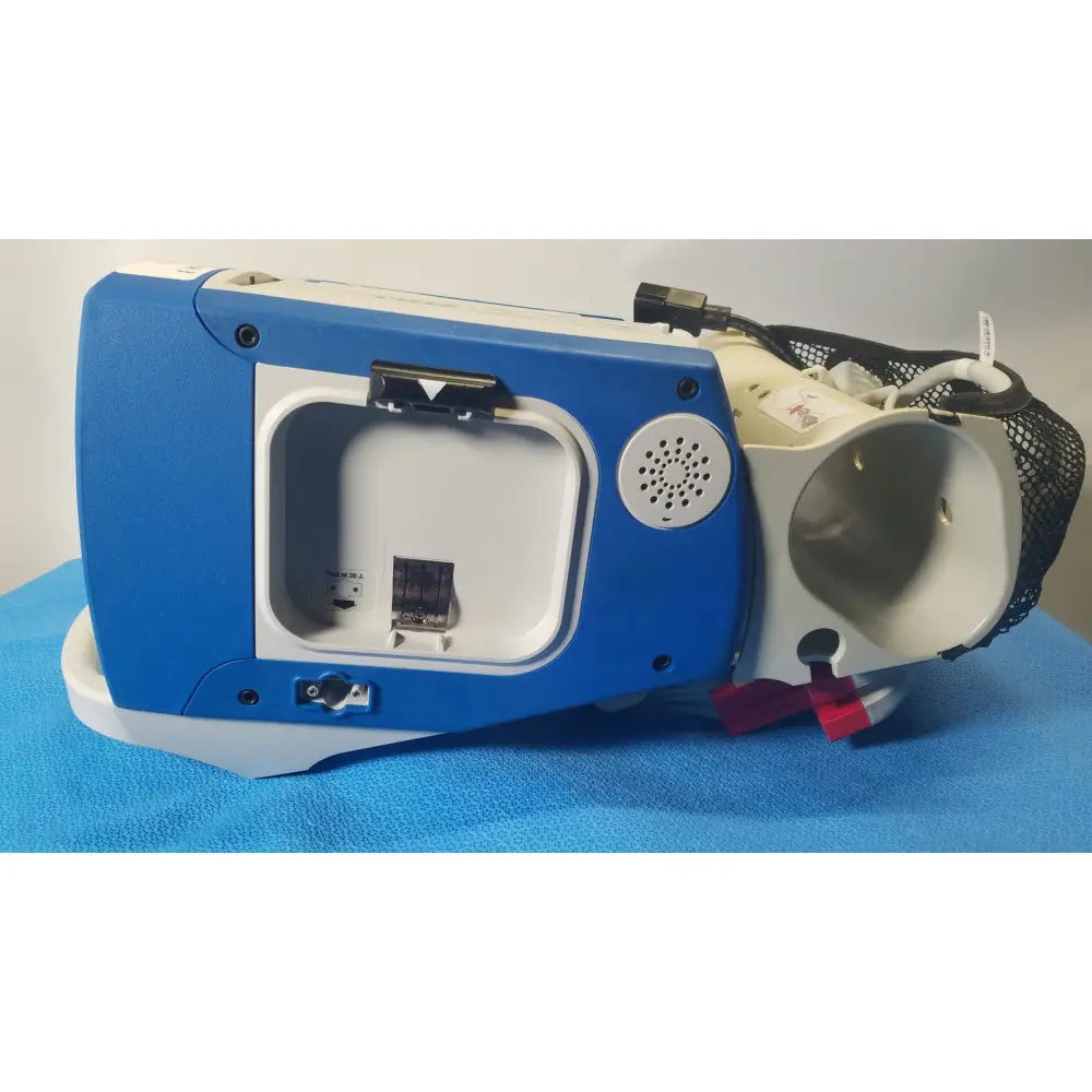 Blue and white portable oxygen concentrator with mesh tubing compartment on the back of zoll r series als patient monitor