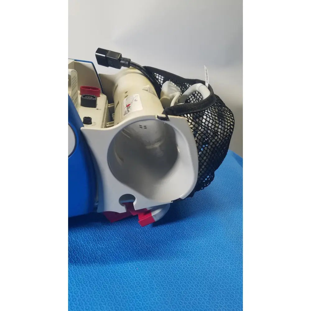 Blue and white electric vacuum cleaner with black mesh carrying bag attached shown alongside zoll r series als patient monitor