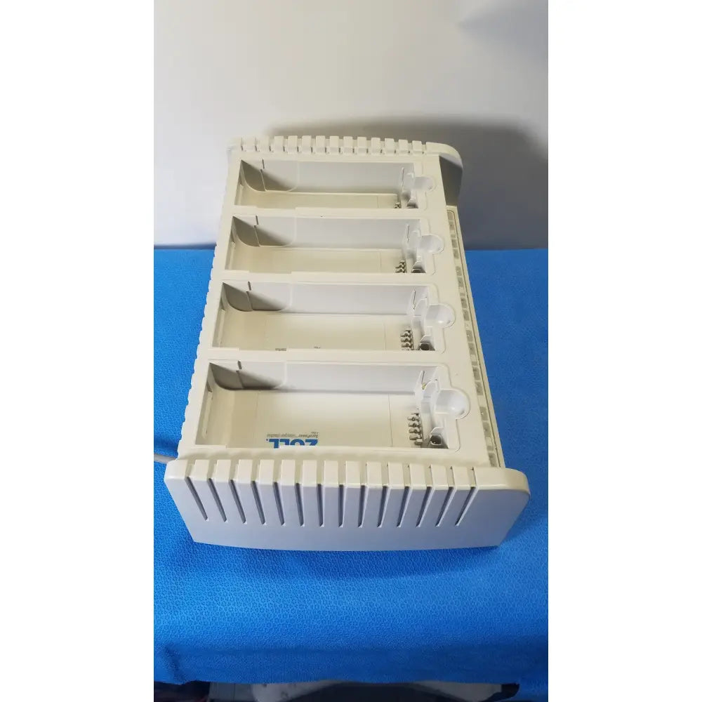 White plastic zoll surepower bay charger station ipx1 with four slots and blue logo for efficient battery charging