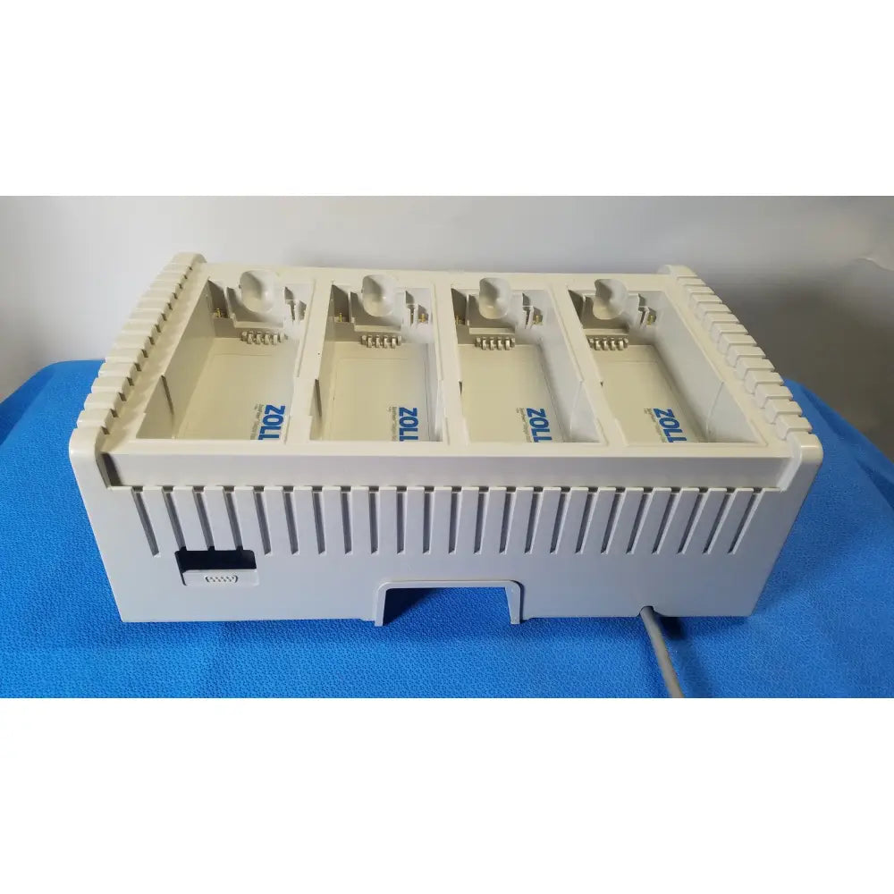 White plastic zoll surepower bay charger station ipx1 with four compartments and blue branding for battery charging