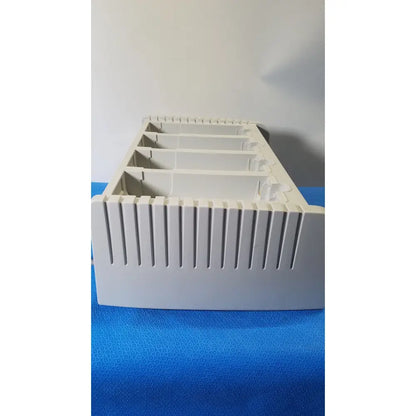 White plastic zoll surepower bay charger station ipx1 with five compartments and vertical ridges on front edge